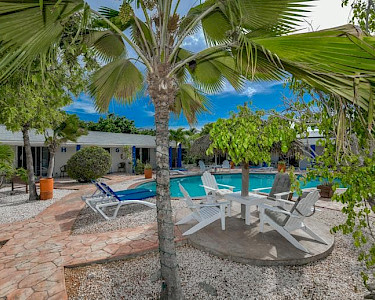 Hacienda Wayaca Aruba zitje langs het zwembad en palmboom