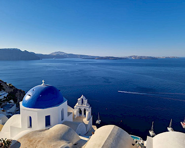 Blauwe koepel op Santorini met uitzicht op zee